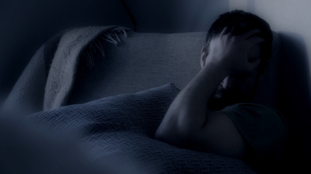 Muškarac u krevetu izgleda uznemireno i uplašeno nakon burnog sna