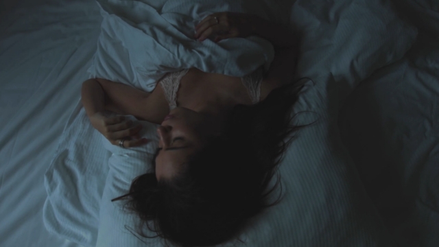 Žena leži budna u krevetu u tamnoj sobi